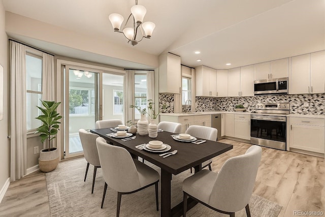 2552 E 126th Way, Thornton, CO 80241 - dining area featuring light wood finished floors, a chandelier, vaulted ceiling, and recessed lighting