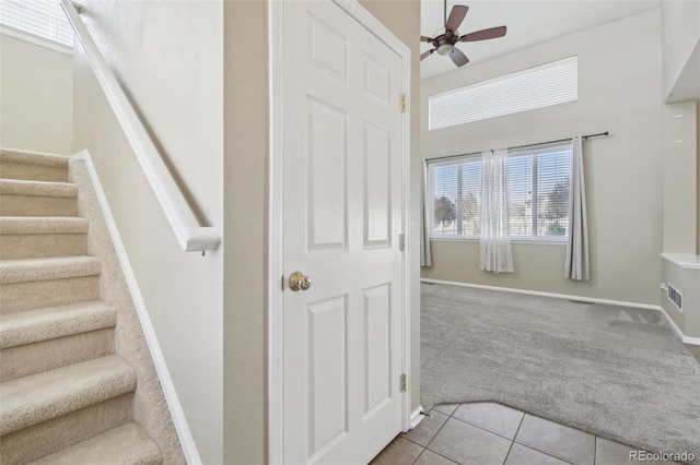 stairway featuring tile patterned floors, baseboards, carpet floors, and a ceiling fan