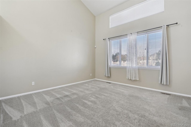 carpeted spare room featuring visible vents, baseboards, and high vaulted ceiling