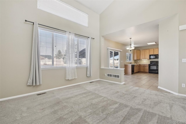 unfurnished living room featuring a notable chandelier, visible vents, light tile patterned floors, and light carpet