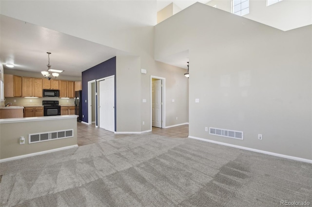 unfurnished living room with a notable chandelier, light colored carpet, visible vents, and baseboards