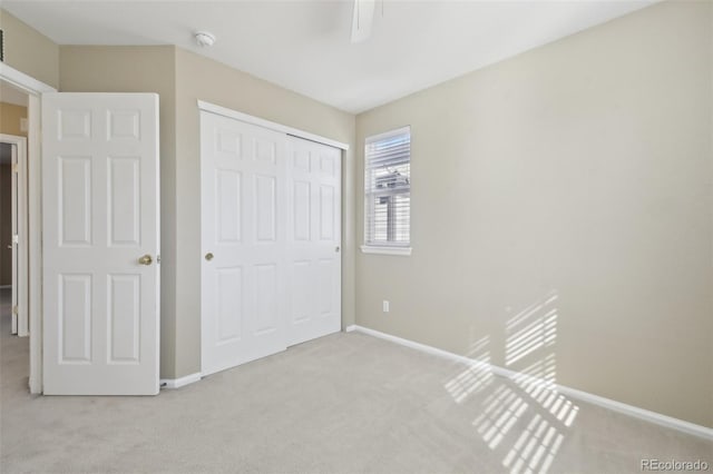 unfurnished bedroom with ceiling fan, carpet, a closet, and baseboards