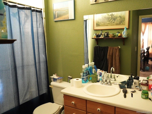 full bathroom with toilet, a textured wall, a shower with shower curtain, and vanity