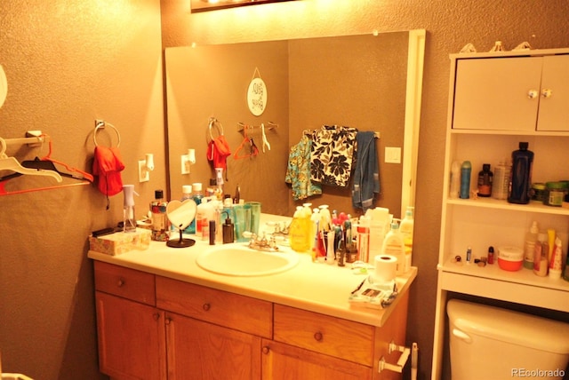 bathroom with toilet, a textured wall, and vanity