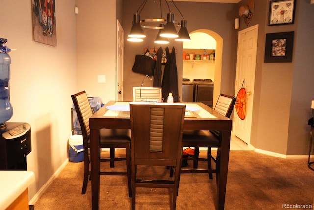 carpeted dining room with arched walkways, baseboards, washing machine and clothes dryer, and a chandelier