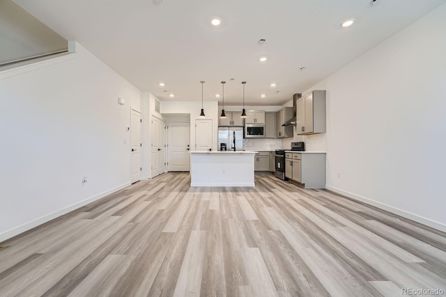 kitchen featuring a center island, hanging light fixtures, appliances with stainless steel finishes, gray cabinets, and decorative backsplash