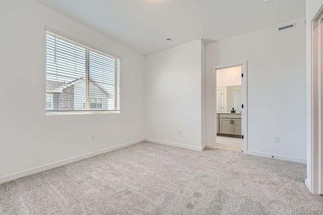 unfurnished bedroom featuring ensuite bath and light carpet