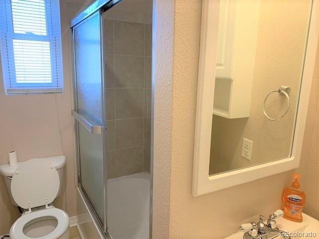 bathroom featuring combined bath / shower with glass door and toilet