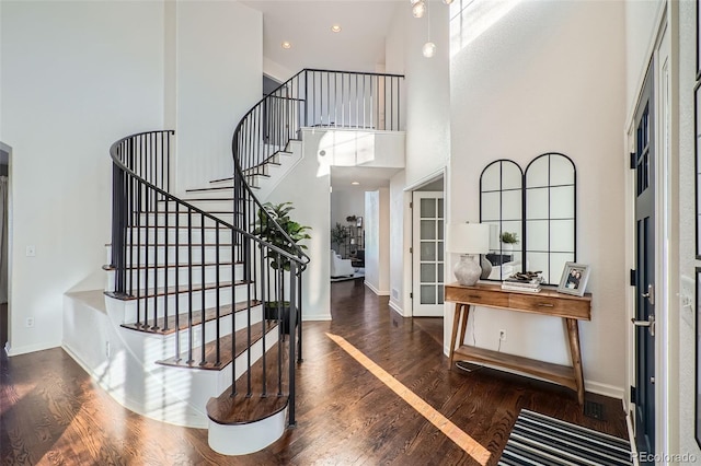 entryway featuring a towering ceiling and dark wood-type flooring