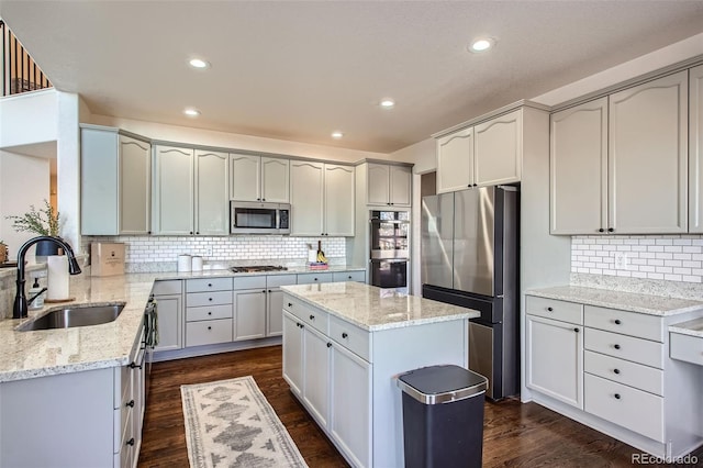 kitchen featuring sink, a kitchen island, light stone counters, and appliances with stainless steel finishes