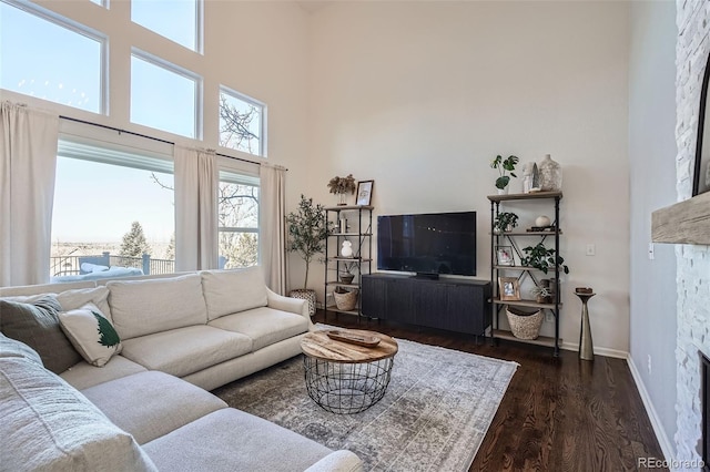 living room featuring a towering ceiling, a fireplace, and dark hardwood / wood-style floors