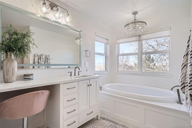 bathroom featuring a healthy amount of sunlight, a tub to relax in, a chandelier, and vanity