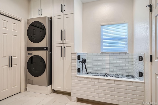 laundry room featuring stacked washer / dryer and light tile patterned floors