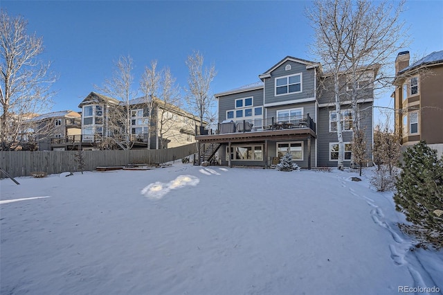 snow covered rear of property with a wooden deck