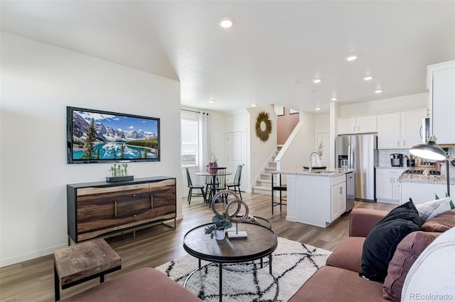 living room featuring recessed lighting, baseboards, light wood finished floors, and stairs