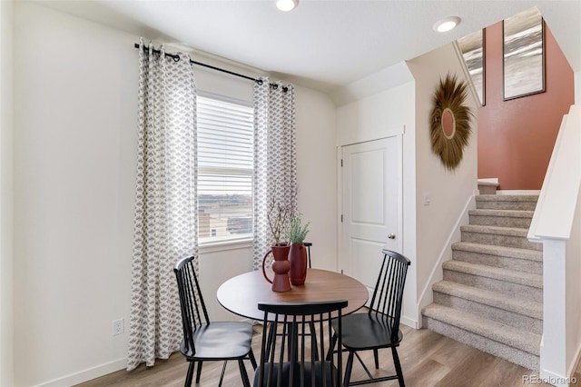 dining area with light wood-type flooring, recessed lighting, baseboards, and stairway