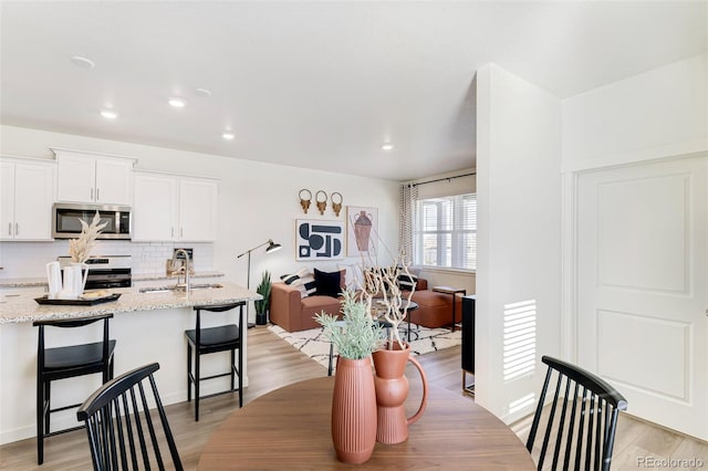 dining area with light wood-style floors and recessed lighting