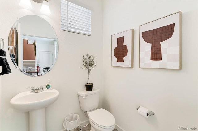 bathroom featuring toilet, baseboards, and a sink