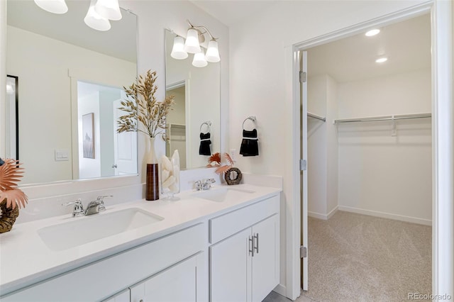 full bath featuring a sink, a walk in closet, recessed lighting, and double vanity