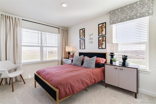 bedroom featuring baseboards, multiple windows, and light colored carpet