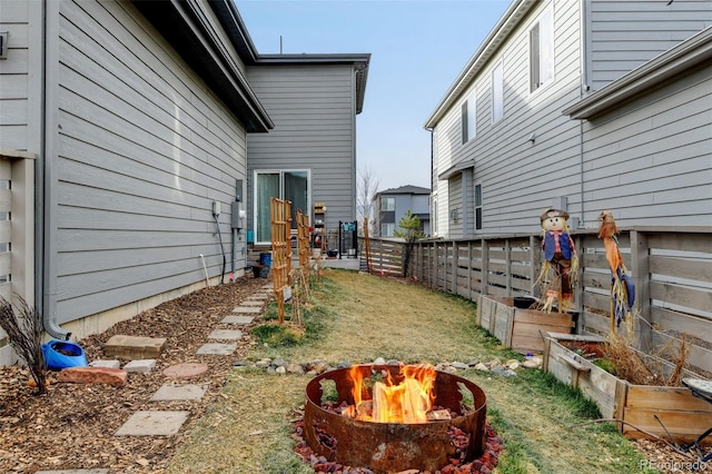 view of yard with a fire pit, fence, and a garden