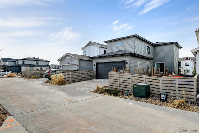 view of front facade featuring a garage, driveway, fence, and a residential view