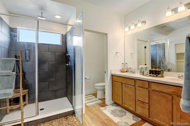 bathroom with wood finished floors, a sink, toilet, and a shower stall