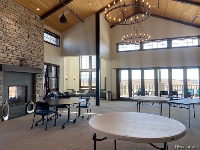 dining area with wood ceiling, light carpet, a notable chandelier, and a stone fireplace