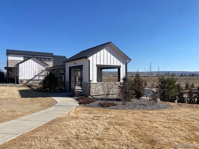 view of front of home featuring board and batten siding, stone siding, and a front lawn