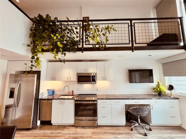 kitchen with stainless steel appliances, white cabinets, and light hardwood / wood-style floors