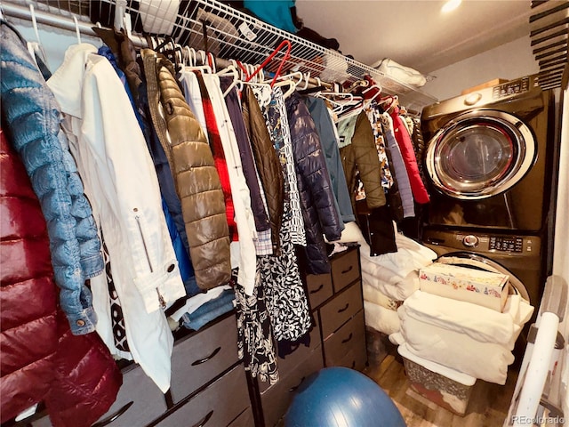 walk in closet with stacked washer and clothes dryer and hardwood / wood-style flooring