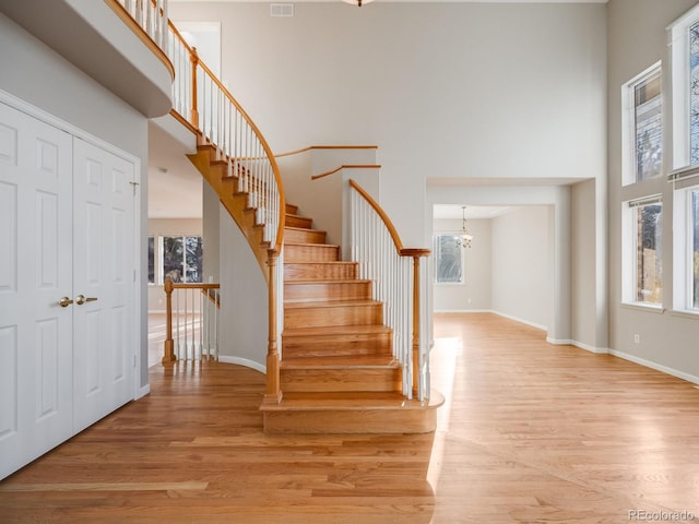 stairs featuring wood-type flooring, a towering ceiling, and a wealth of natural light