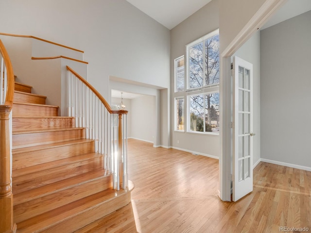 entrance foyer with light wood-type flooring, a wealth of natural light, and high vaulted ceiling