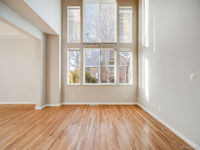 unfurnished room featuring a high ceiling and light wood-type flooring