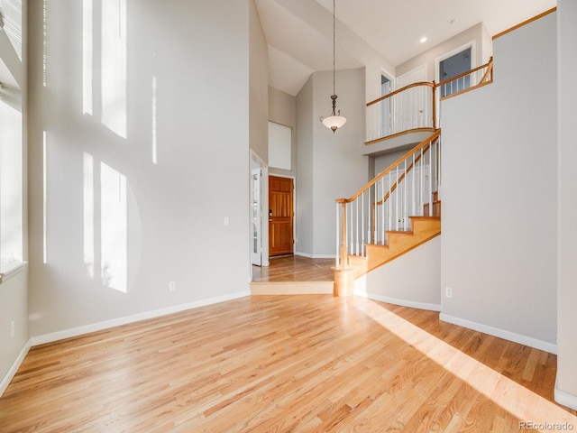 entryway featuring a towering ceiling and light wood-type flooring