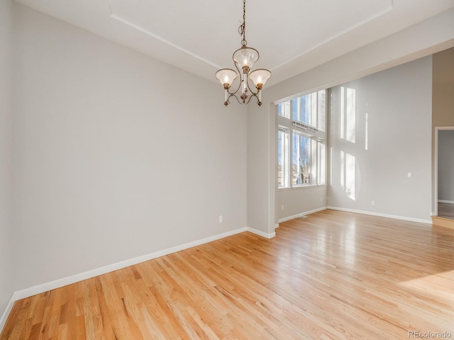 spare room with light hardwood / wood-style floors and a chandelier