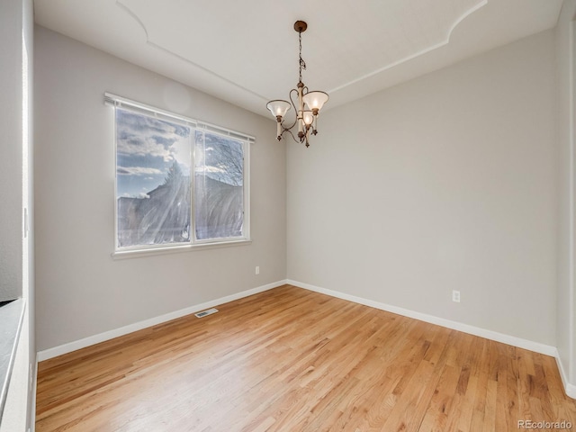 empty room featuring a notable chandelier and hardwood / wood-style flooring