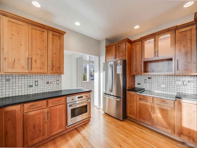 kitchen featuring appliances with stainless steel finishes, light hardwood / wood-style floors, and decorative backsplash