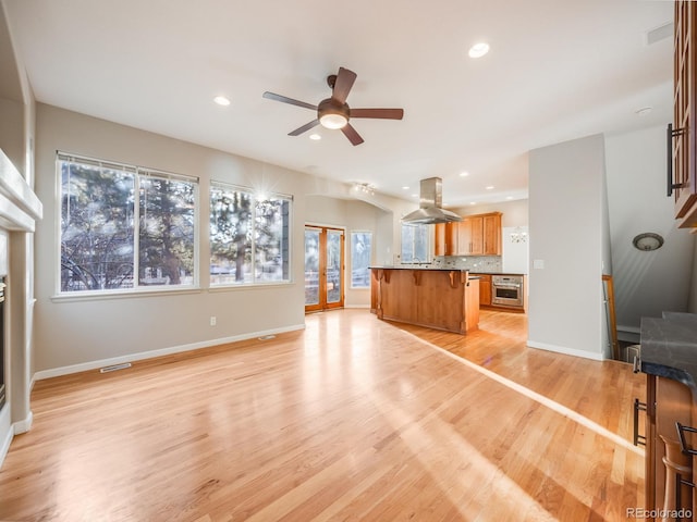 unfurnished living room with ceiling fan and light wood-type flooring