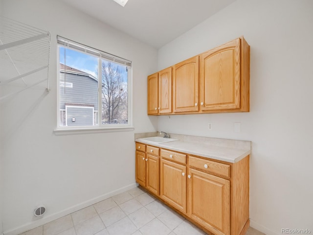 clothes washing area featuring cabinets, sink, and light tile patterned floors