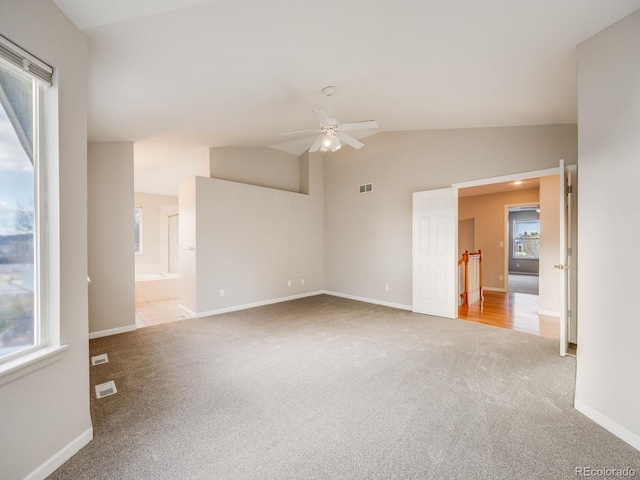 empty room featuring lofted ceiling, light carpet, and ceiling fan