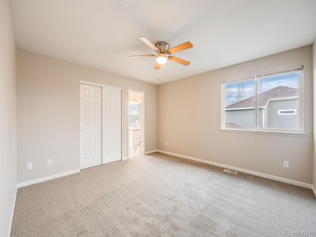 unfurnished bedroom with connected bathroom, carpet floors, a closet, and ceiling fan