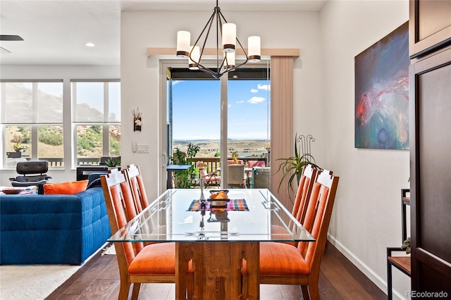 dining space featuring dark wood-type flooring and an inviting chandelier