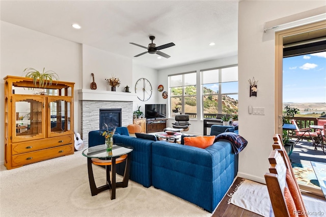 living room with ceiling fan, light wood-type flooring, and a fireplace