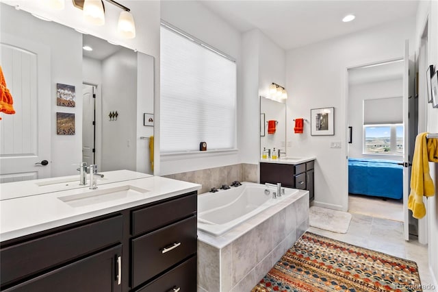 bathroom with tile patterned flooring, vanity, and tiled tub