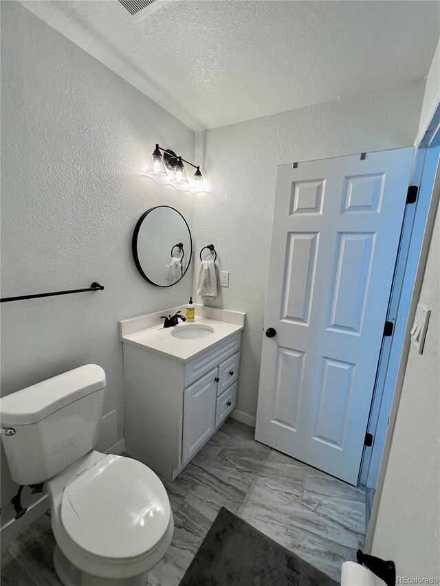 4178 E 94th Pl, Thornton, CO 80229 - bathroom with a textured wall, vanity, toilet, a textured ceiling, and marble look tile flooring