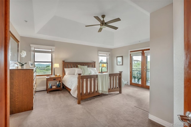 carpeted bedroom with access to exterior, multiple windows, and a raised ceiling