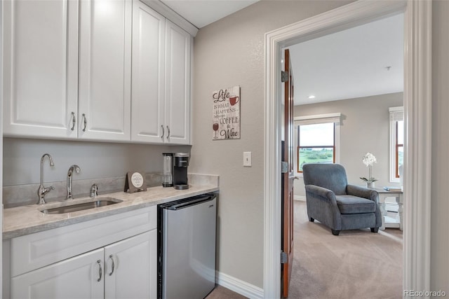 indoor wet bar with refrigerator, light carpet, and baseboards