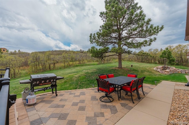 view of patio featuring outdoor dining area, area for grilling, and a view of trees