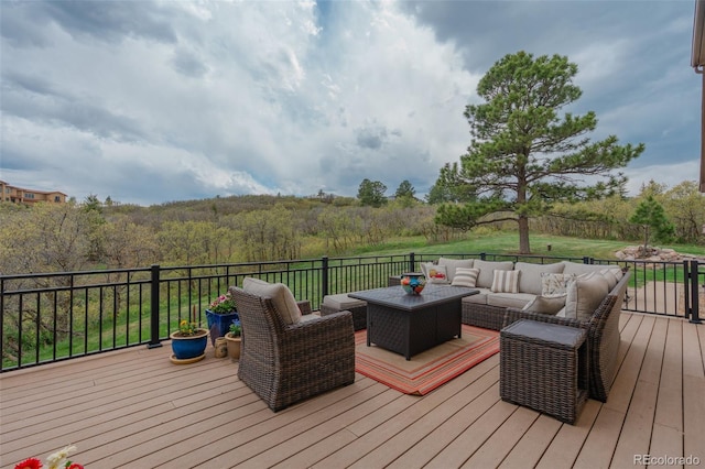 wooden deck with an outdoor hangout area and a view of trees